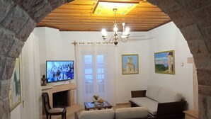 Een gezellige woonkamer met een open haard, een televisie, een bank en een kroonluchter.