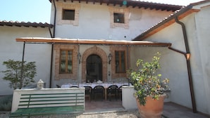 A patio with a table set for dining, a bench, and a potted plant. - Two-room apartment in old villa with pool located between Lucca and Florence (Pistoia)