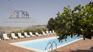 Zona de piscina con sillones de descanso y vistas a las colinas.