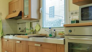 Una cocina con armarios de madera, estufa, horno y una ventana con persianas.