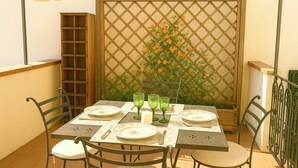 Un comedor con una mesa dispuesta para cuatro personas, sillas alrededor y una estantería de madera a la izquierda.