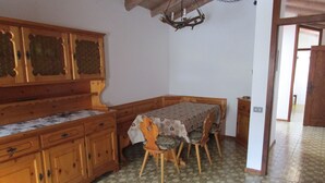 Ein Zimmer mit einem Holzesstisch, Stühlen, einem Holzschrank und ornamentierten Bodenfliesen.