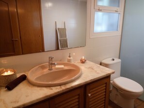 Un baño con lavamanos, espejo y retrete.