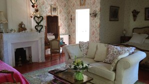 Una sala de estar acogedora con chimenea, papel tapiz floral, un sofá y una mesa de centro con un florero.