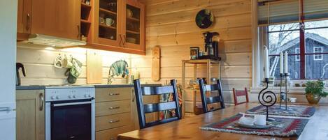 A cozy kitchen with wooden cabinets, a stove, and a dining table with chairs.