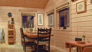 L'intérieur d'un chalet en bois, avec une table à manger, des chaises et une petite table d'appoint.