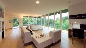 A modern living room with a large window, a sofa, a coffee table, and a desk with a computer. - Spectacular designer house, with heated pool, 8 minutes from the beach. (Ea)