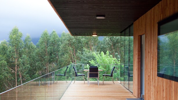 A modern outdoor deck with a glass balustrade, wooden flooring, and a table with chairs. - Spectacular designer house, with heated pool, 8 minutes from the beach. (Ea)