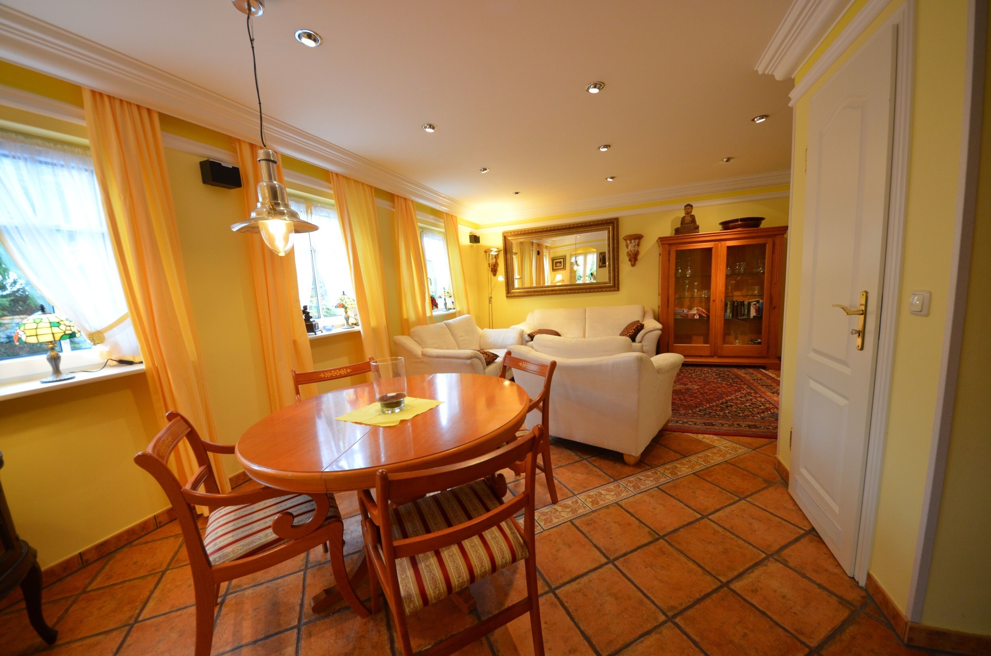 A living room with a dining table, chairs, a sofa, and a cabinet.