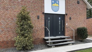 Een gebouw van baksteen met een zwarte deur en een familiewapen erboven.