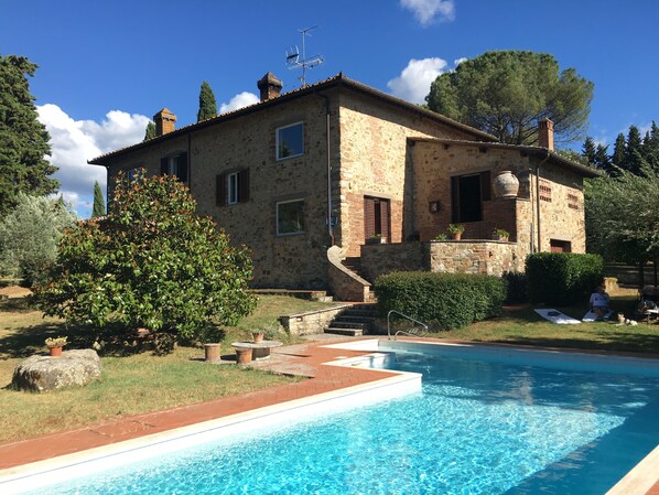 Una villa de piedra con piscina, una escalera de piedra y un jardín.