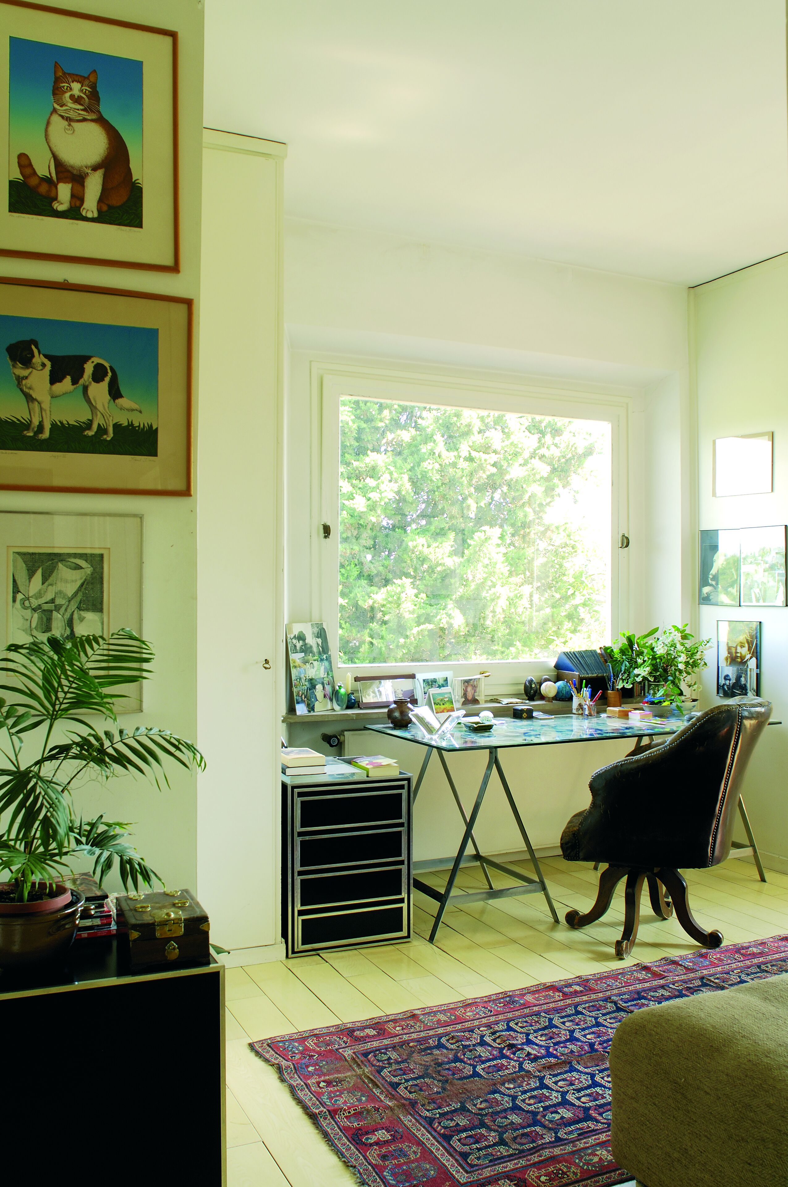 A room with a desk, a chair, a large window, and a rug.