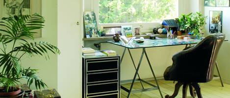 A room with a desk, a chair, a large window, and a rug.