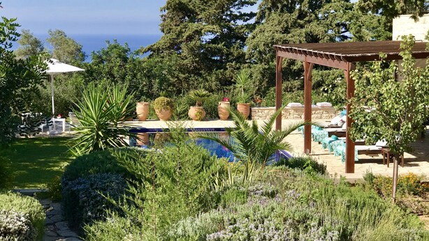 A pool area with lounge chairs and a pergola, surrounded by lush greenery and potted plants. - Villa LaMori in a quiet location with a heatable pool and a beautiful garden (Nikiforos Fokas)