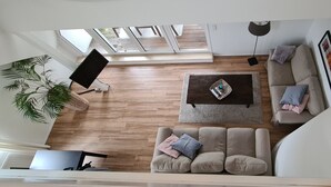 A modern living room with a wooden floor, a beige sofa, a coffee table, and a TV. - Apartment Seeloft with balcony and direct lake view on the Möhnesee  (Möhnesee)