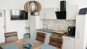 A modern kitchen with white cabinets, a stone backsplash, and a coffee machine. - Apartment waterfront (Waren (Müritz))