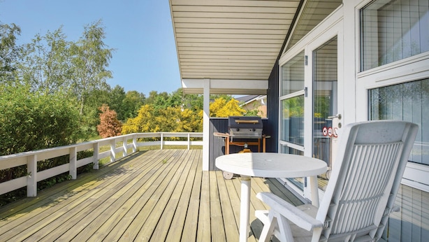 A wooden deck with a white railing, a round table, and a grill. - 3 bedroom cozy home in Humble (Humble)