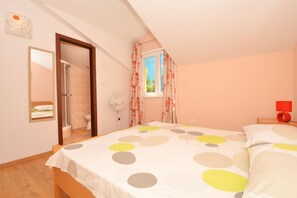 A bedroom with a bed, a fan, a window with curtains, and a mirror. - KATARINA 2 Apartment with a view of the sea, just 20 meters from the pebble beach (Mastrinka)