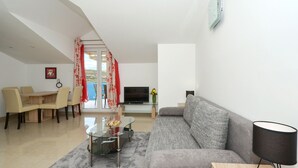 Un soggiorno moderno con un divano, un tavolino in vetro, una televisione e un'area pranzo con sedie e tavolo.