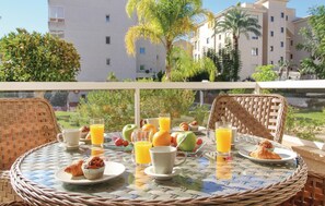 Enjoy breakfast in style with a round table set amidst lush greenery and a residential view.