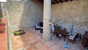A stone-walled patio with a tiled floor, a wooden table with chairs, and a potted plant. - Ulla, Alt Emporda: Holiday home in a small, quiet historic village.  (Ulla, Torroella de Montgri)