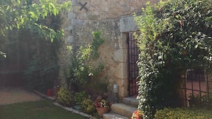 A stone building with a small window and a door, surrounded by greenery and a stone pathway. - Ulla, Alt Emporda: Holiday home in a small, quiet historic village.  (Ulla, Torroella de Montgri)