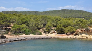 A coastal landscape with a beach, rocky shoreline, and dense forested hills in the background. - Ulla, Alt Emporda: Holiday home in a small, quiet historic village.  (Ulla, Torroella de Montgri)