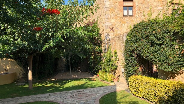 A stone building with a window and a door, surrounded by greenery and a stone pathway. - Ulla, Alt Emporda: Holiday home in a small, quiet historic village.  (Ulla, Torroella de Montgri)