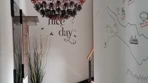 A modern staircase with a wooden finish, a decorative wall with a 'nice day' sign, and a map with landmarks. - Modern & TOP-equipped apartment (up to 6 pers.) + Netflix + bicycle garage (Uhldingen/Mühlhofen)