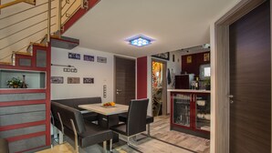 A modern dining area with a wooden staircase, a dining table with chairs, and a kitchen area with cabinets and a refrigerator. - Modern & TOP-equipped apartment (up to 6 pers.) + Netflix + bicycle garage (Uhldingen/Mühlhofen)