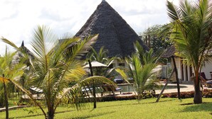 A resort with a pyramid-shaped building, palm trees, and a pool area. - Stunning villa Twiga in African style with Wi-Fi (Diani Beach)