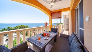Un balcone con un tavolo apparecchiato per la colazione, una ventola a soffitto e vista sul mare.