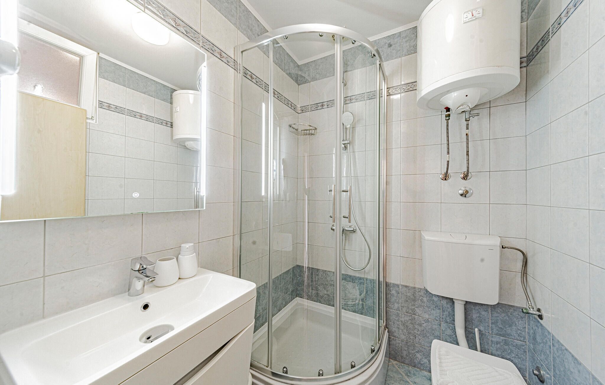 Une salle de bain moderne avec une douche à parois de verre, un lavabo blanc et des toilettes.