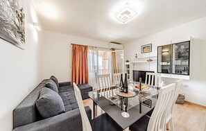 Ein modernes Wohnzimmer mit einer Couch, einem Esstisch und einem Kamin.