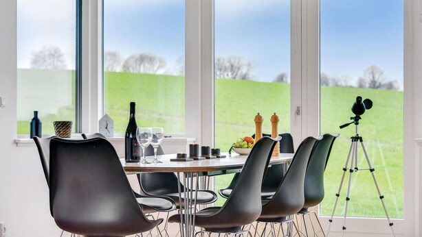 A dining area with a table set for four, chairs, a telescope, and a view of a green field. - Awesome home in Augustenborg with WiFi (Augustenborg)