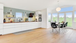 A modern kitchen with white cabinets, a wooden countertop, and a dining area with a table and chairs. - Awesome home in Augustenborg with WiFi (Augustenborg)