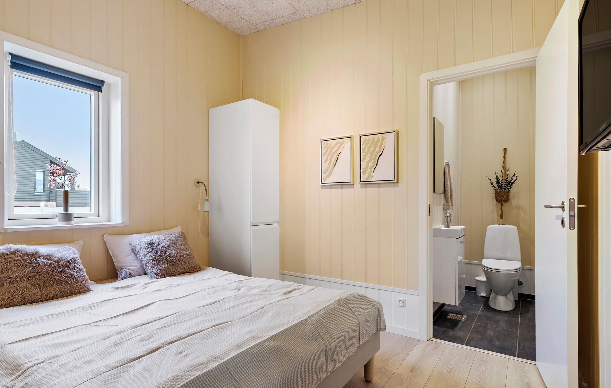 Une chambre à coucher avec un lit, une armoire et une salle de bain visible à travers une porte ouverte.