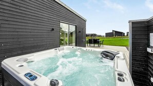 Ett bubbelbad med en kontrollpanel, en glasdörr och en uteplats med utemöbler.