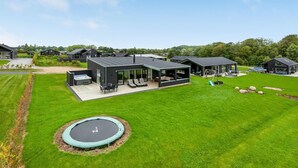 Ett modernt bostadskomplex med flera hus, en swimmingpool och en studsmatta.