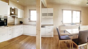 Eine moderne Küche mit weißen Schränken, einem eingebauten Ofen und einem Essbereich mit Holztisch und -stühlen.