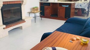 Ein Wohnzimmer mit Kamin, Fernseher und Essbereich mit Tisch und Stühlen.