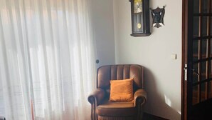 Ein Zimmer mit Ledersessel, Tisch mit Essen, einer Uhr und einem Kleiderständer.