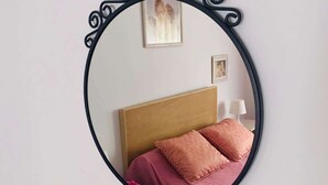 Ein runder Spiegel mit aufwendiger schwarzer Rahmung an einer Wand.