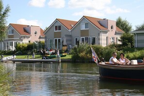 Une rangée de maisons modernes avec un quai et un bateau.