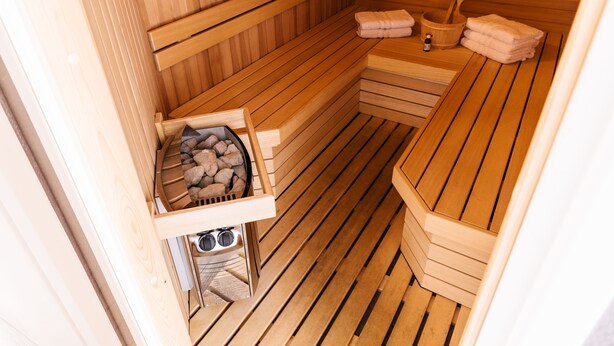 A sauna with wooden benches, a stone basin, and towels.