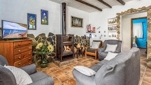 Una sala de estar acogedora con chimenea, pared de piedra y televisor sobre un mueble de madera.