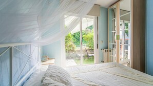 Un dormitorio con una cama grande, una puerta corrediza de vidrio al exterior y un armario con espejo.