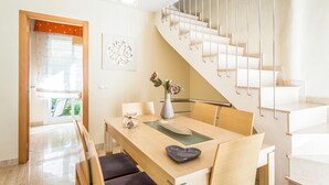 Una cocina moderna con una mesa de madera, sillas, un florero con flores y una escalera.