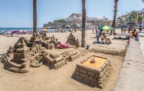 Une plage de sable avec un grand château de sable et des palmiers.