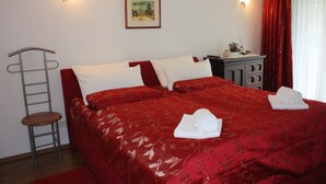 A hotel room with a large bed, two bedside tables, a chair, a dresser, and a painting on the wall.